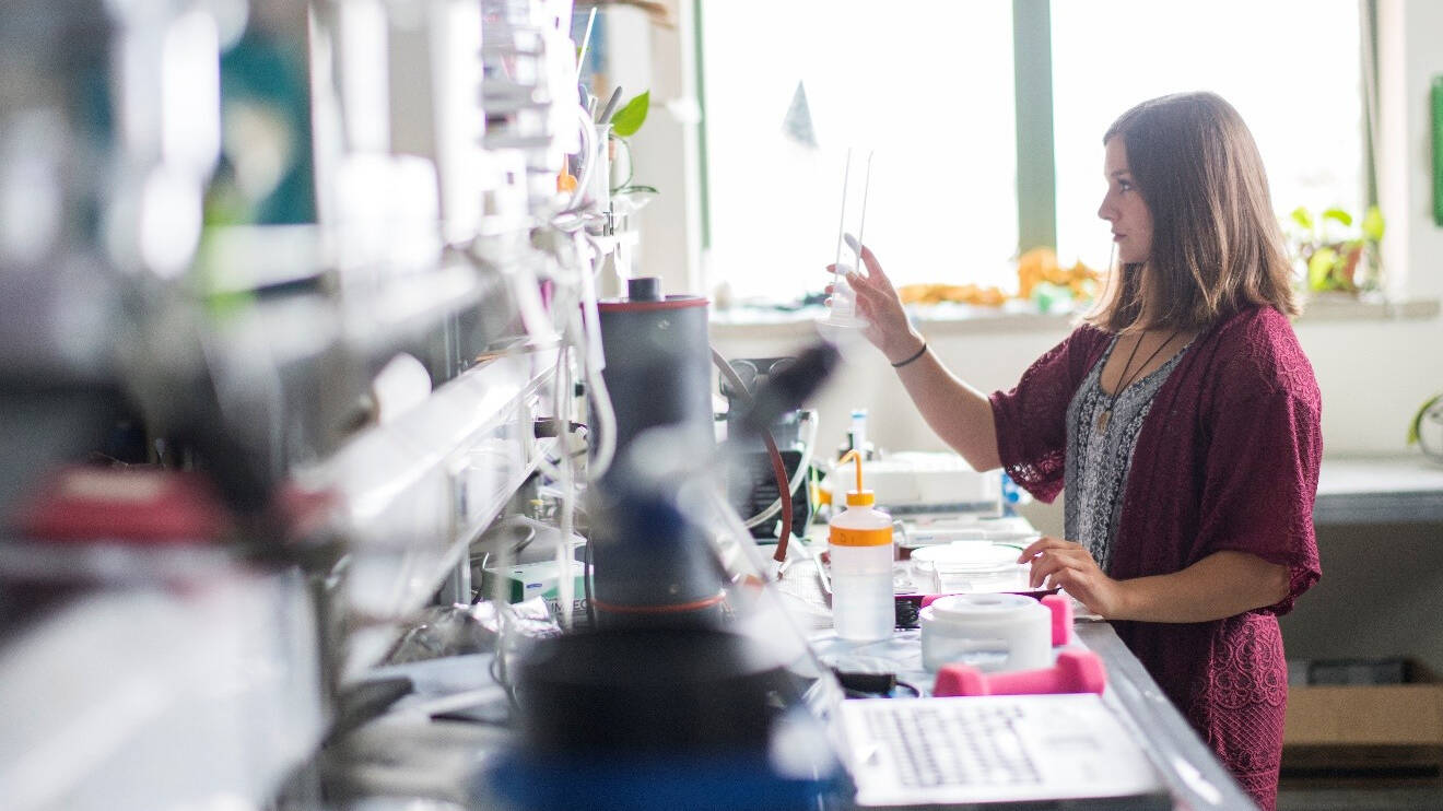 An AWRI graduate student holds chemistry glassware in a laboratory.